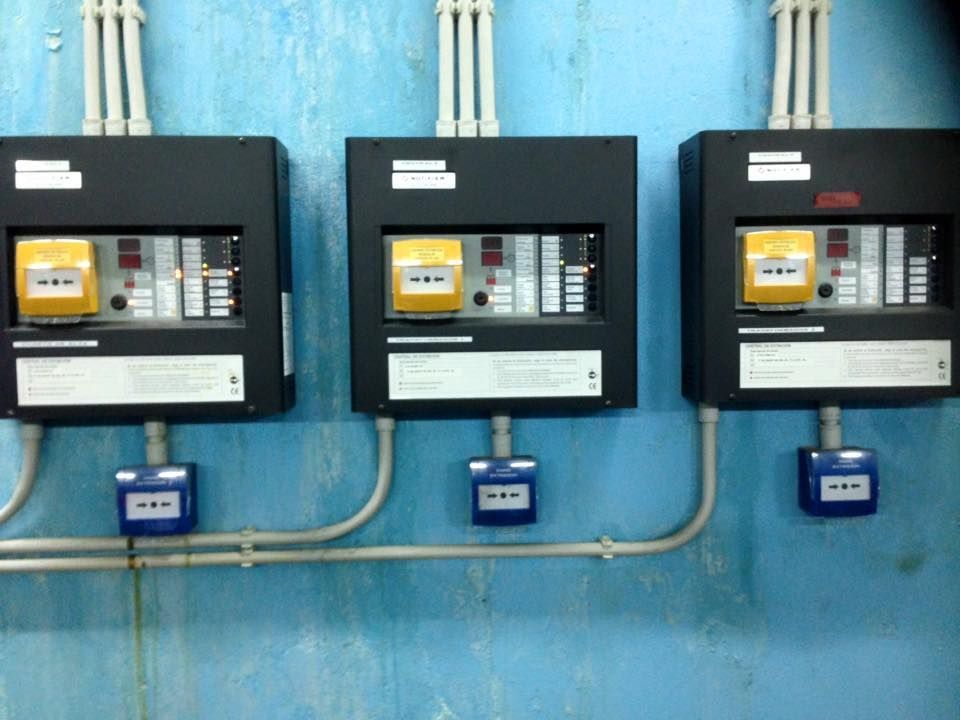 Tres cajas eléctricas están alineadas en una pared azul.