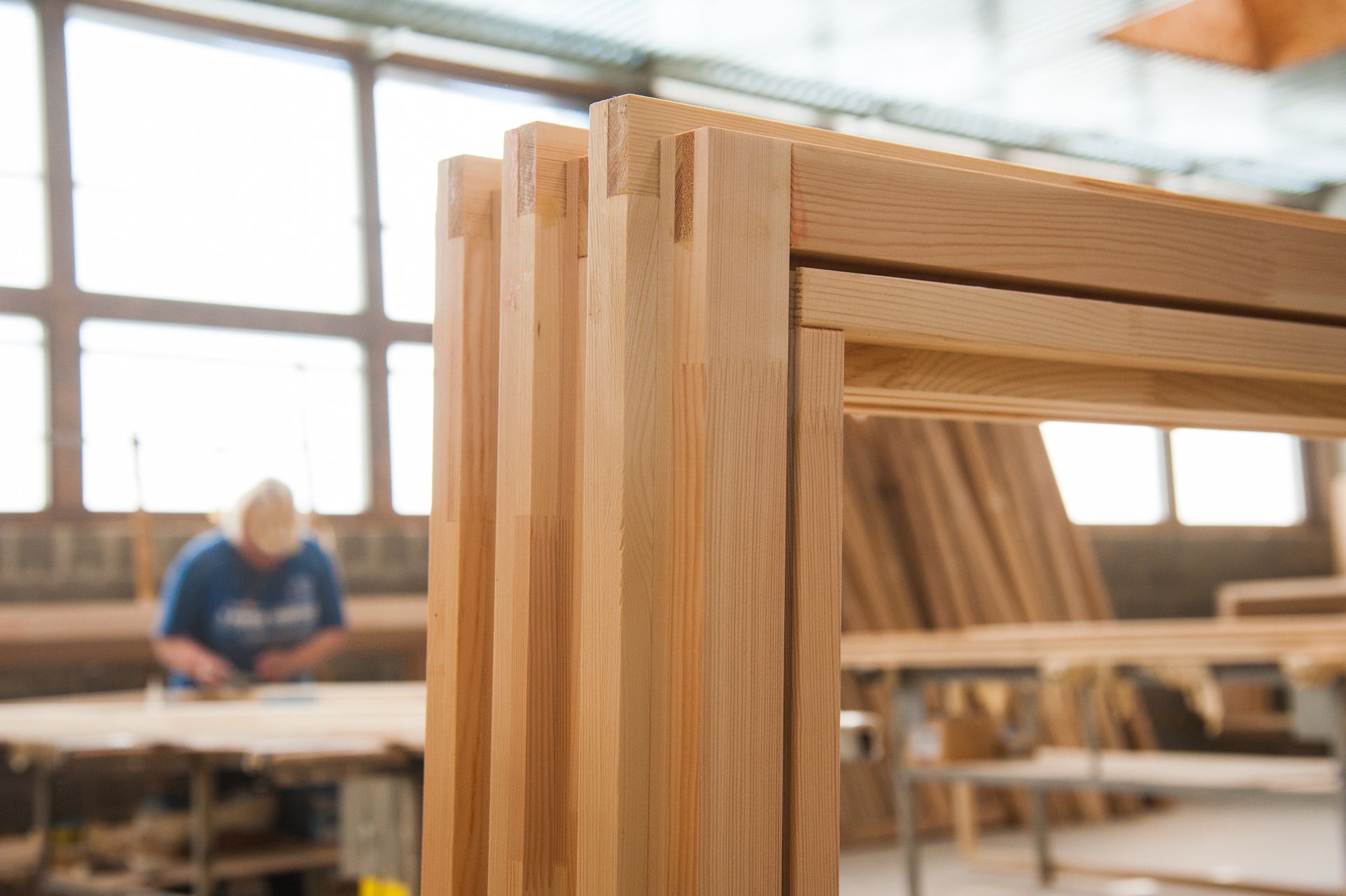 Menuisier dans son atelier derrière une rangée de cadres en bois