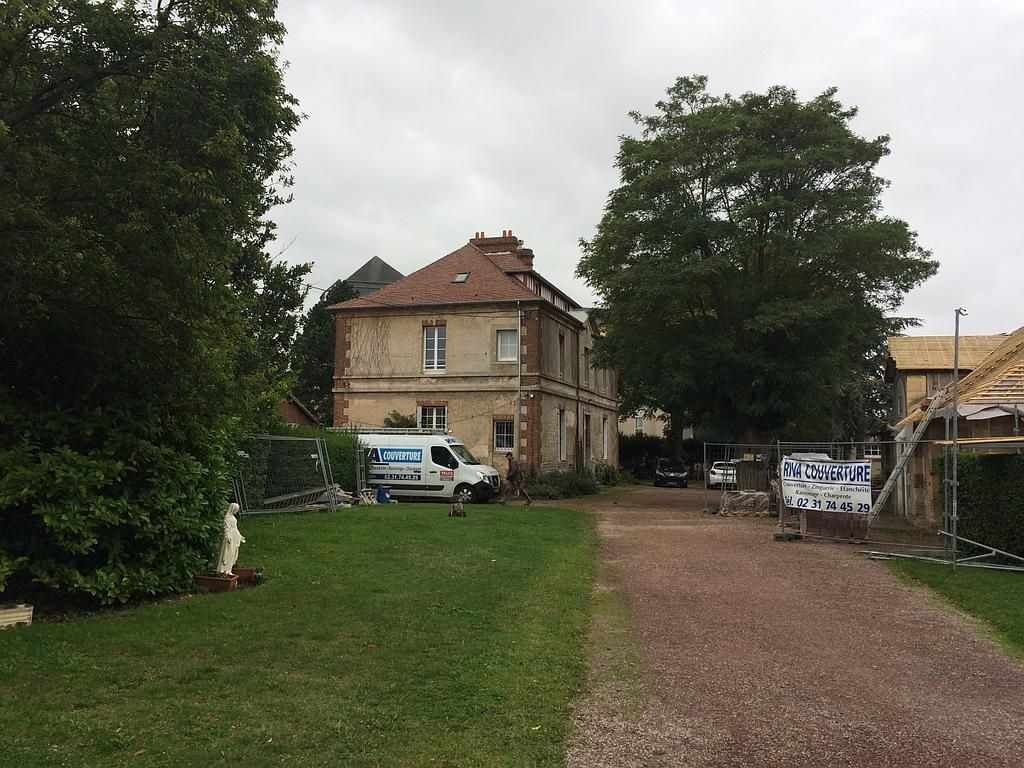 Chantier de travaux de couverture avec camion de l'entreprise en fond