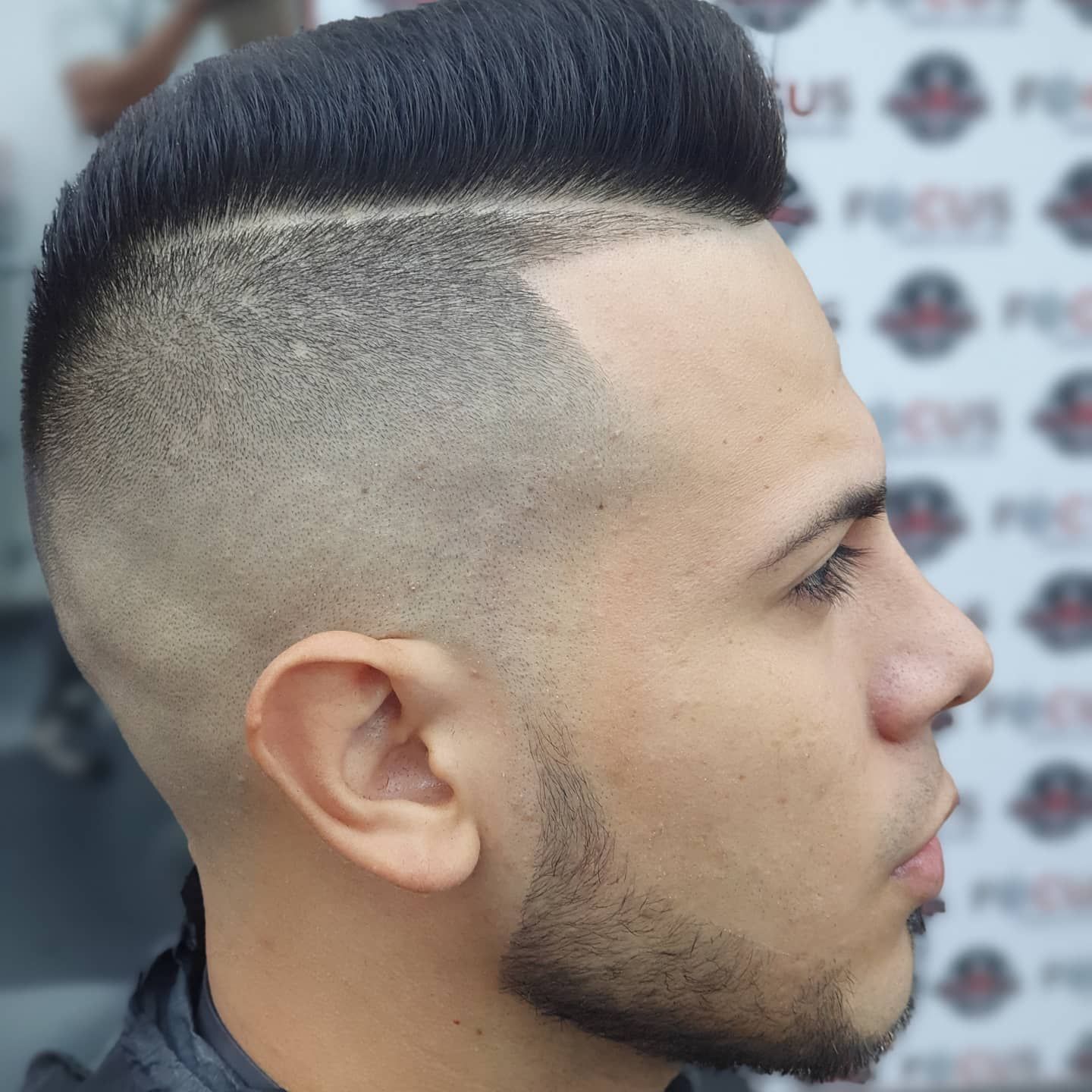 Hombre con corte de pelo alto degradado, cabello negro en la parte superior y piel descolorida en los costados.