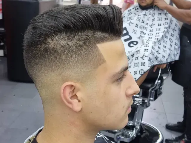 Hombre con corte de pelo degradado, peinado hacia arriba. En una barbería.