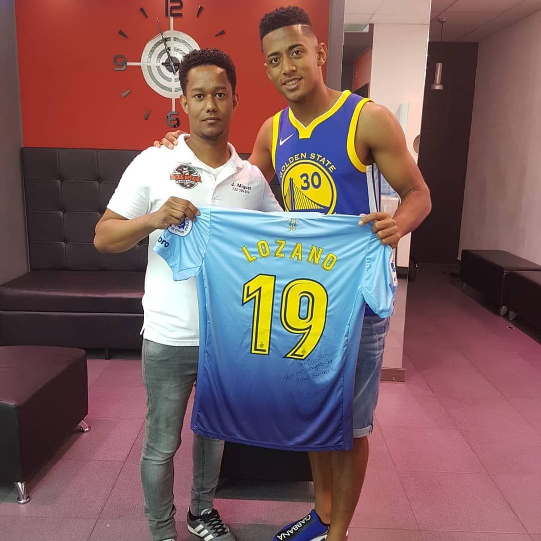 Dos hombres sostienen una camiseta azul claro con