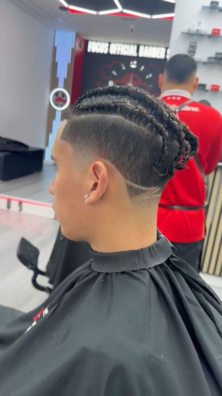 Persona con cabello trenzado y corte desvanecido en una barbería.