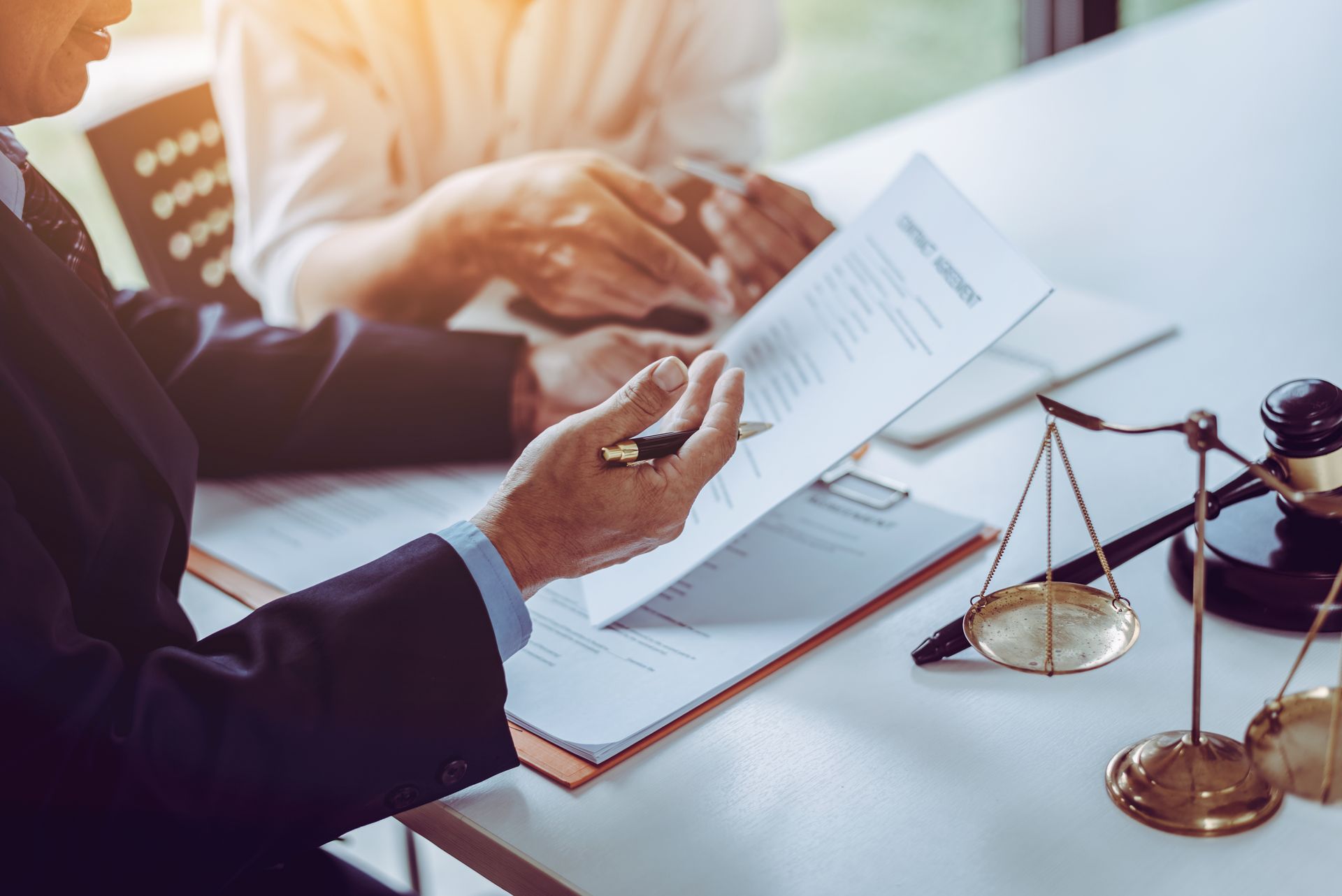 Un avocat examine des documents à un bureau où se trouvent une balance et un marteau.