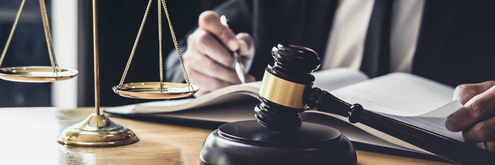 Le marteau du juge, la balance de la justice et un livre de lois ouvert sur un bureau dans une salle d'audience