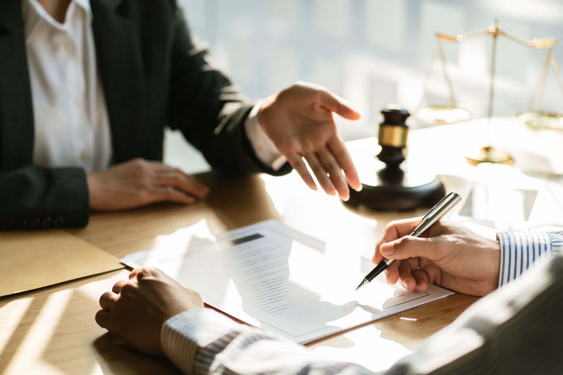 Des avocats examinent un document à un bureau, une main faisant un geste et l'autre signant avec un stylo.