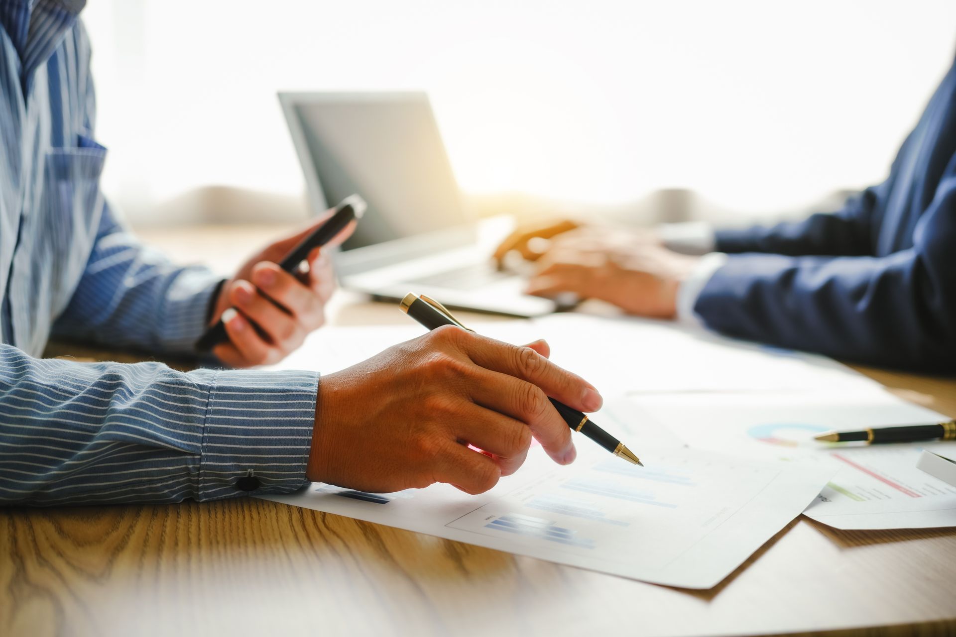 Deux hommes d'affaires examinent des documents ensemble à un bureau avec un ordinateur portable.