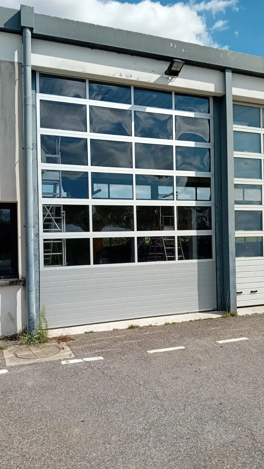 Porte de garage industrielle avec panneaux de verre dans un bâtiment extérieur gris