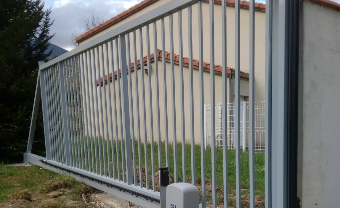 Panneau de clôture métallique courbé, penché vers l'extérieur, à côté d'un bâtiment beige et d'un mur en béton.