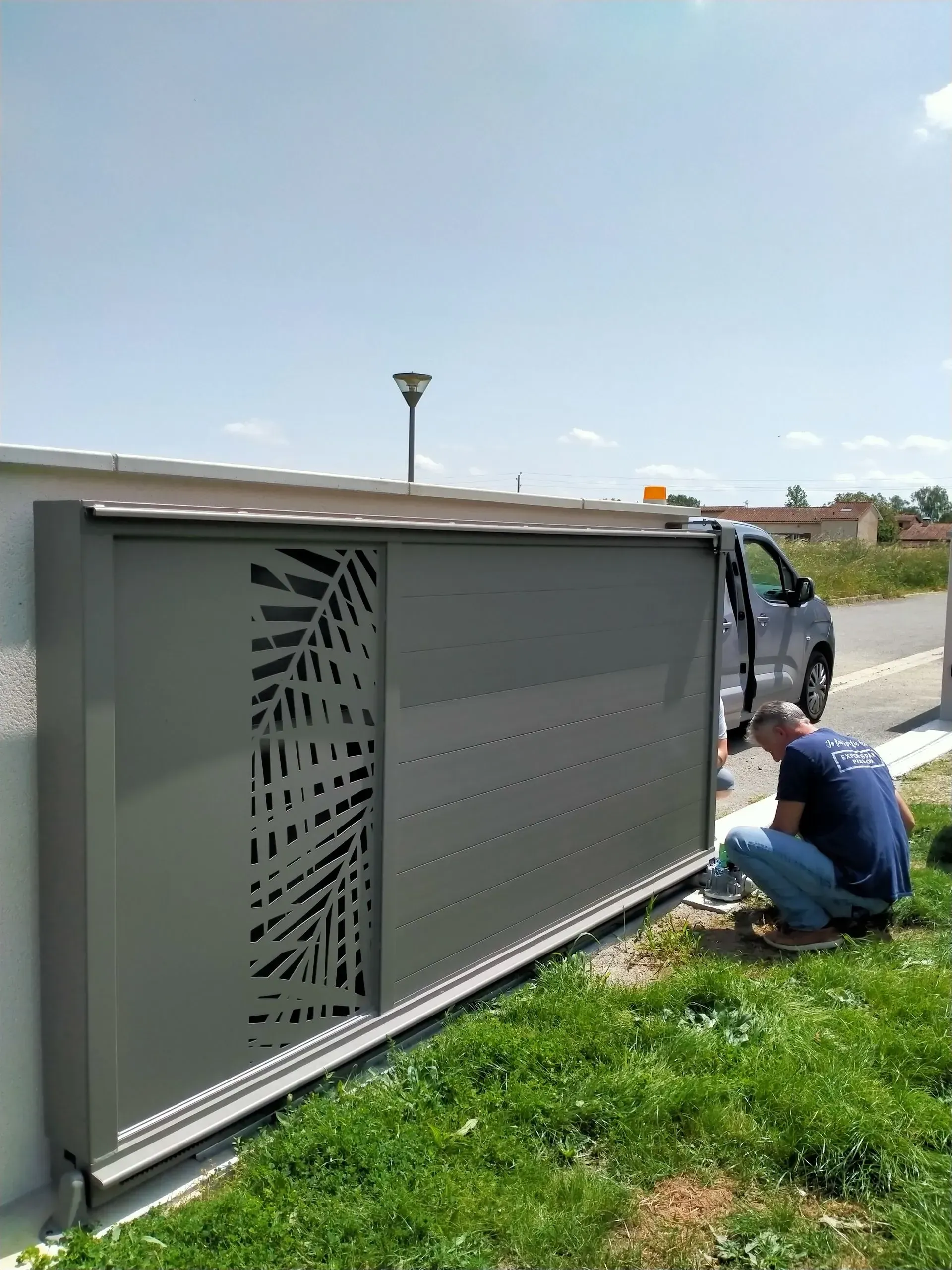Un ouvrier est agenouillé à côté d'un grand boîtier électrique gris à l'extérieur, inspectant le câblage près d'un camion.