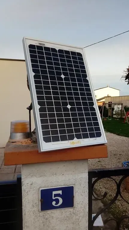 Panneau solaire installé sur un toit à côté de la plaque numéro 5 de la maison.