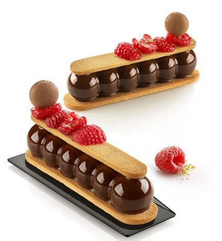 Zwei Desserts mit Schokolade und Himbeeren auf einem schwarzen Teller