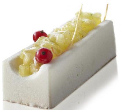Ein weißes Dessert mit Ananas und roten Johannisbeeren auf weißem Untergrund.