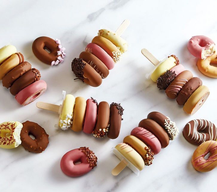 Ein Haufen verschiedenfarbiger Donuts am Stiel auf einem Tisch