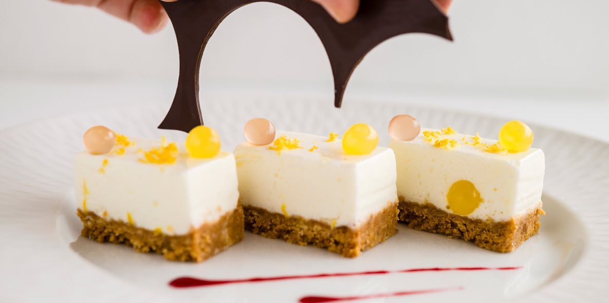 Eine Person dekoriert ein Dessert mit Schokolade auf einem weißen Teller.