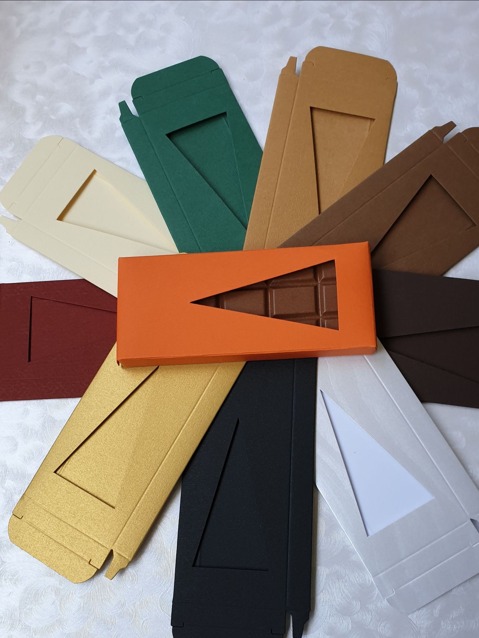 Eine Tafel Schokolade in einer orangefarbenen Schachtel, umgeben von anderen Schachteln