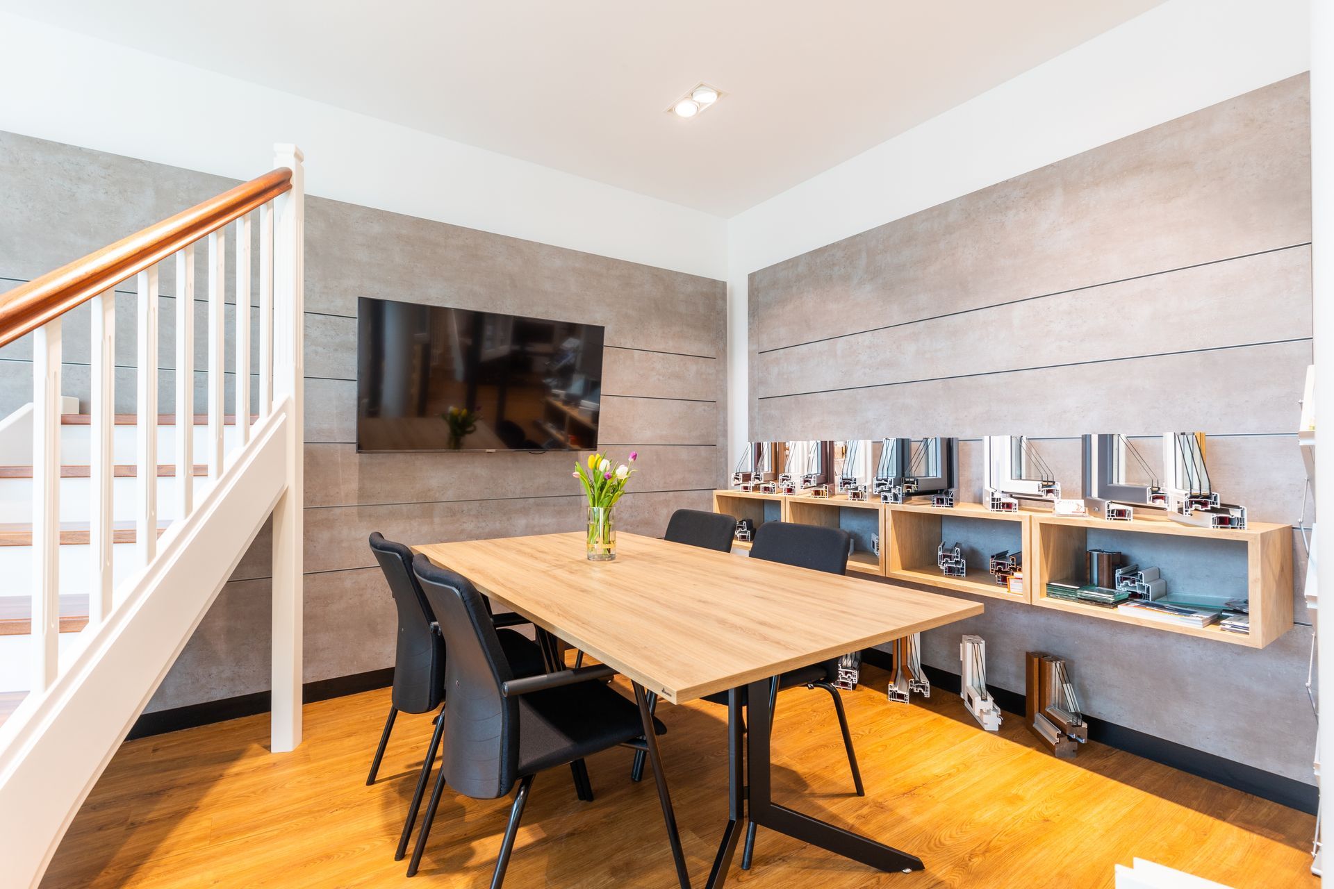 Ein Konferenzraum mit Tisch und Stühlen und einem Fernseher an der Wand.