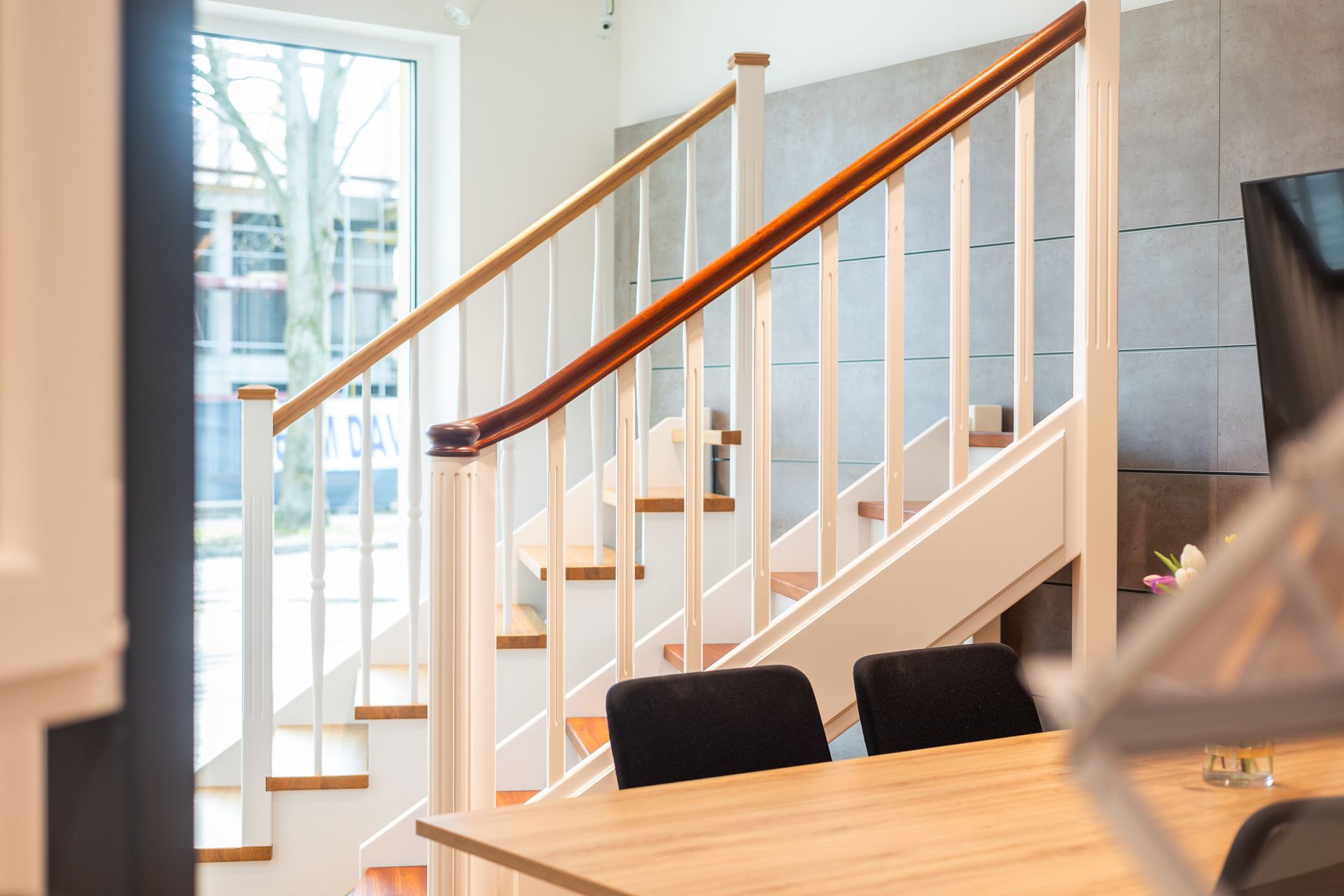 Eine Treppe in einem Haus mit einem Holzgeländer und einem Tisch davor.