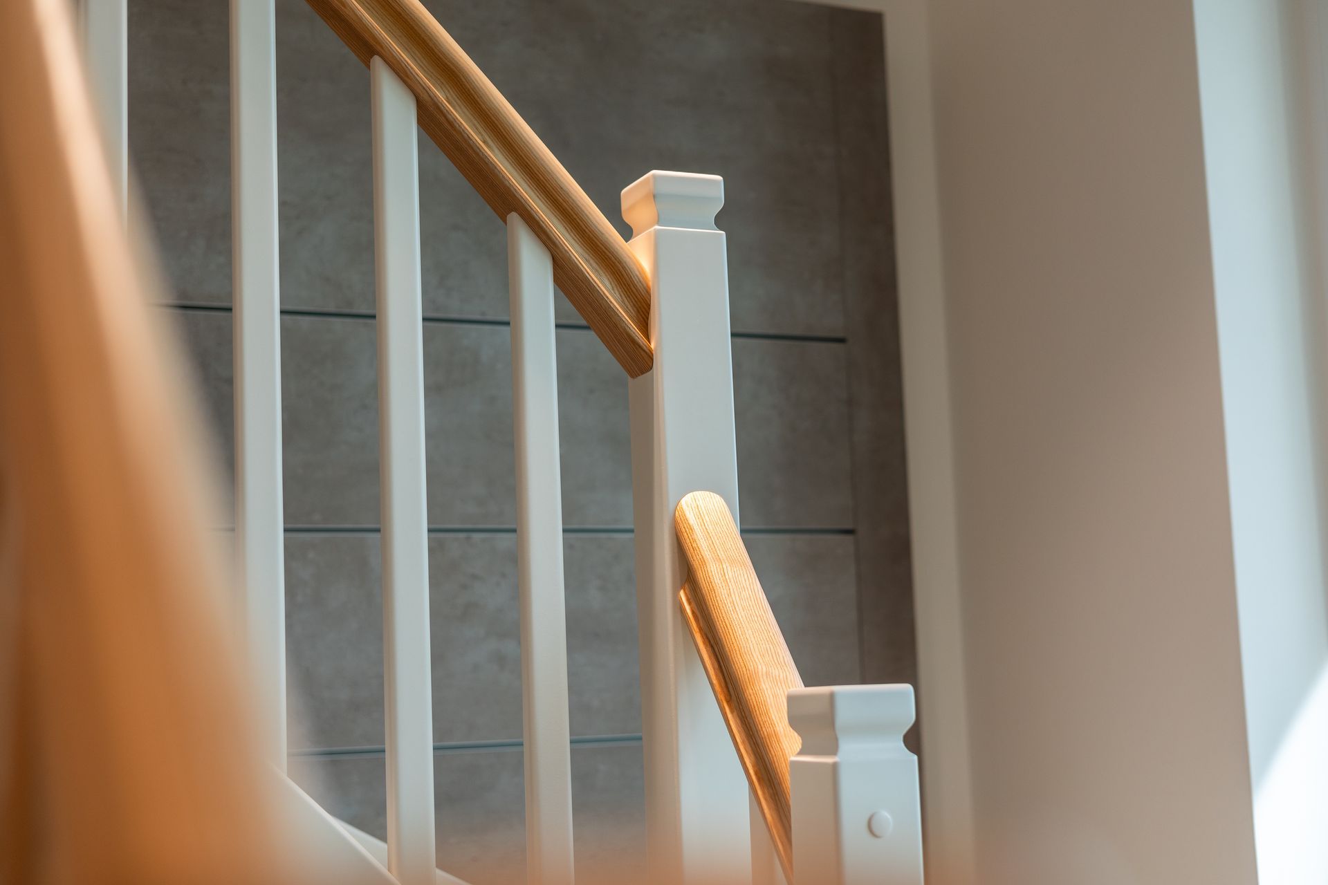 Eine Nahaufnahme einer weißen Treppe mit einem Holzgeländer.