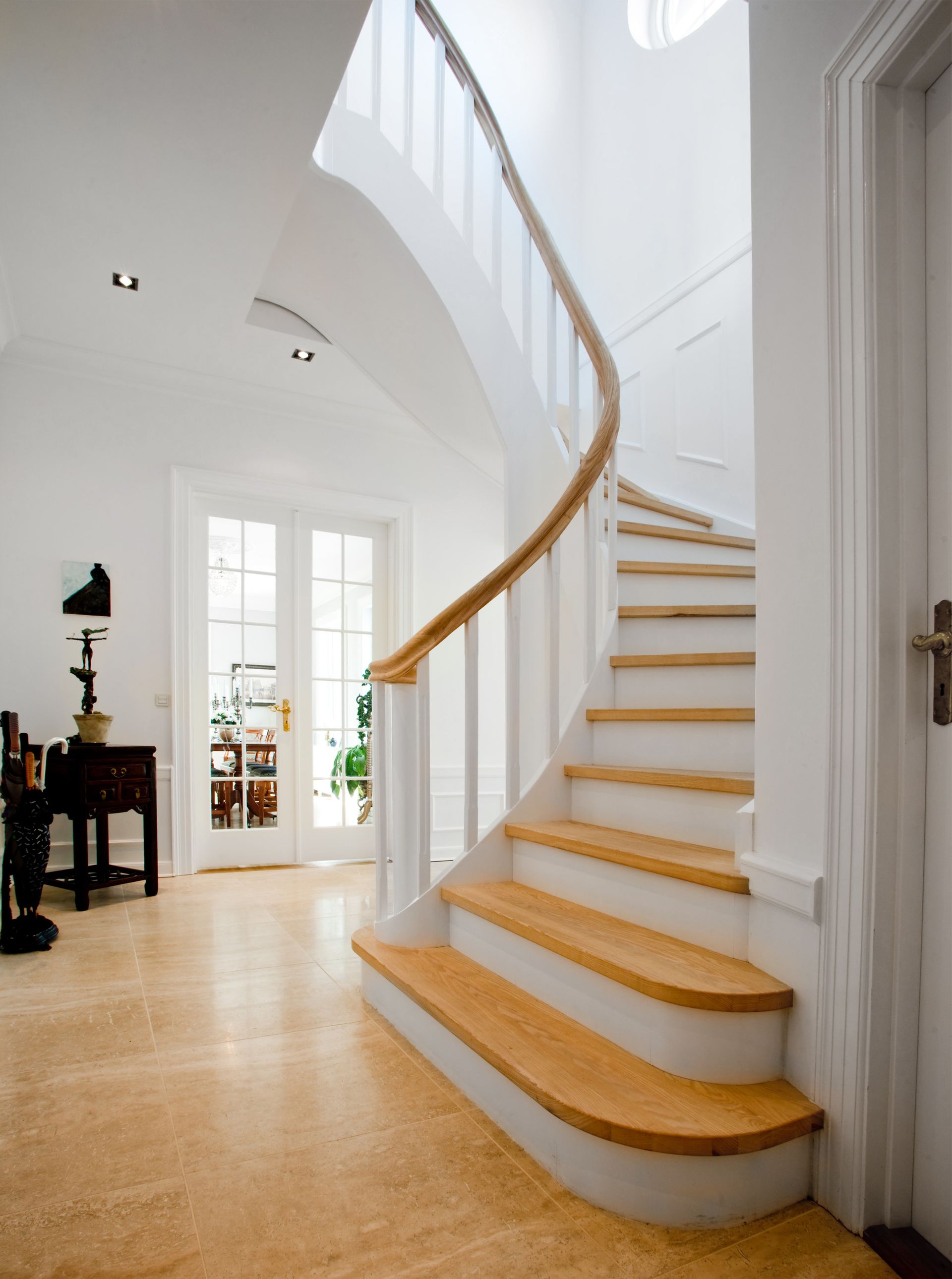 Eine geschwungene Treppe mit Holzstufen und weißem Geländer