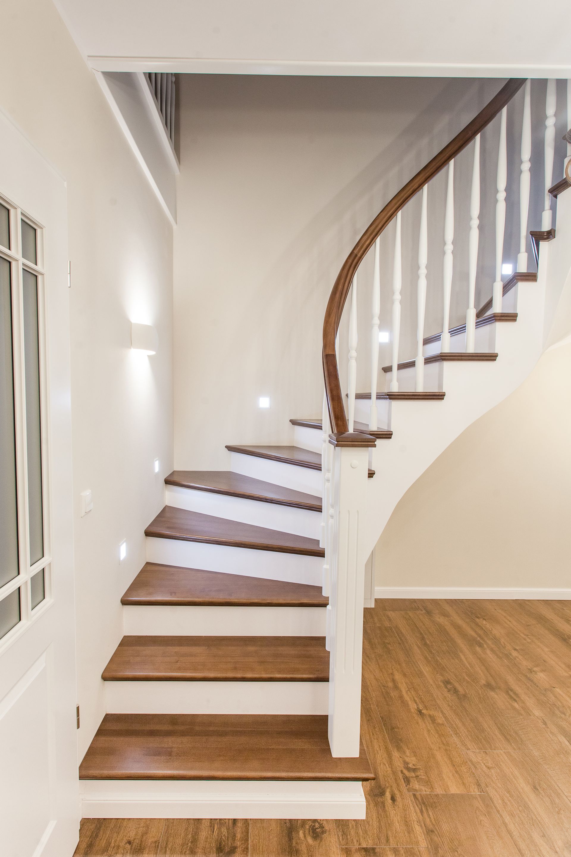 Eine geschwungene Treppe mit Holzstufen und weißem Geländer