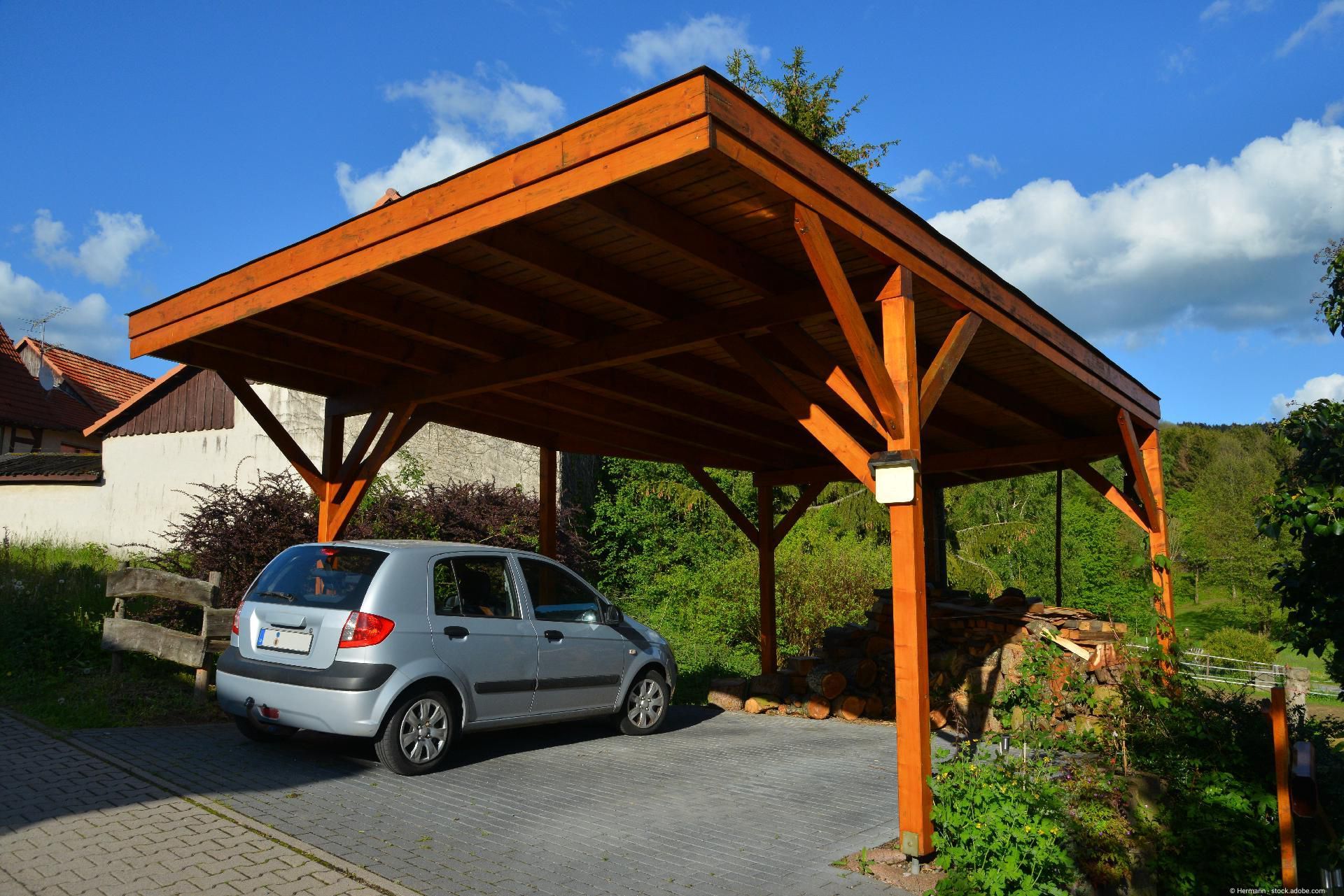 Ein Carport aus Holz mit einem Pickup-Truck darunter