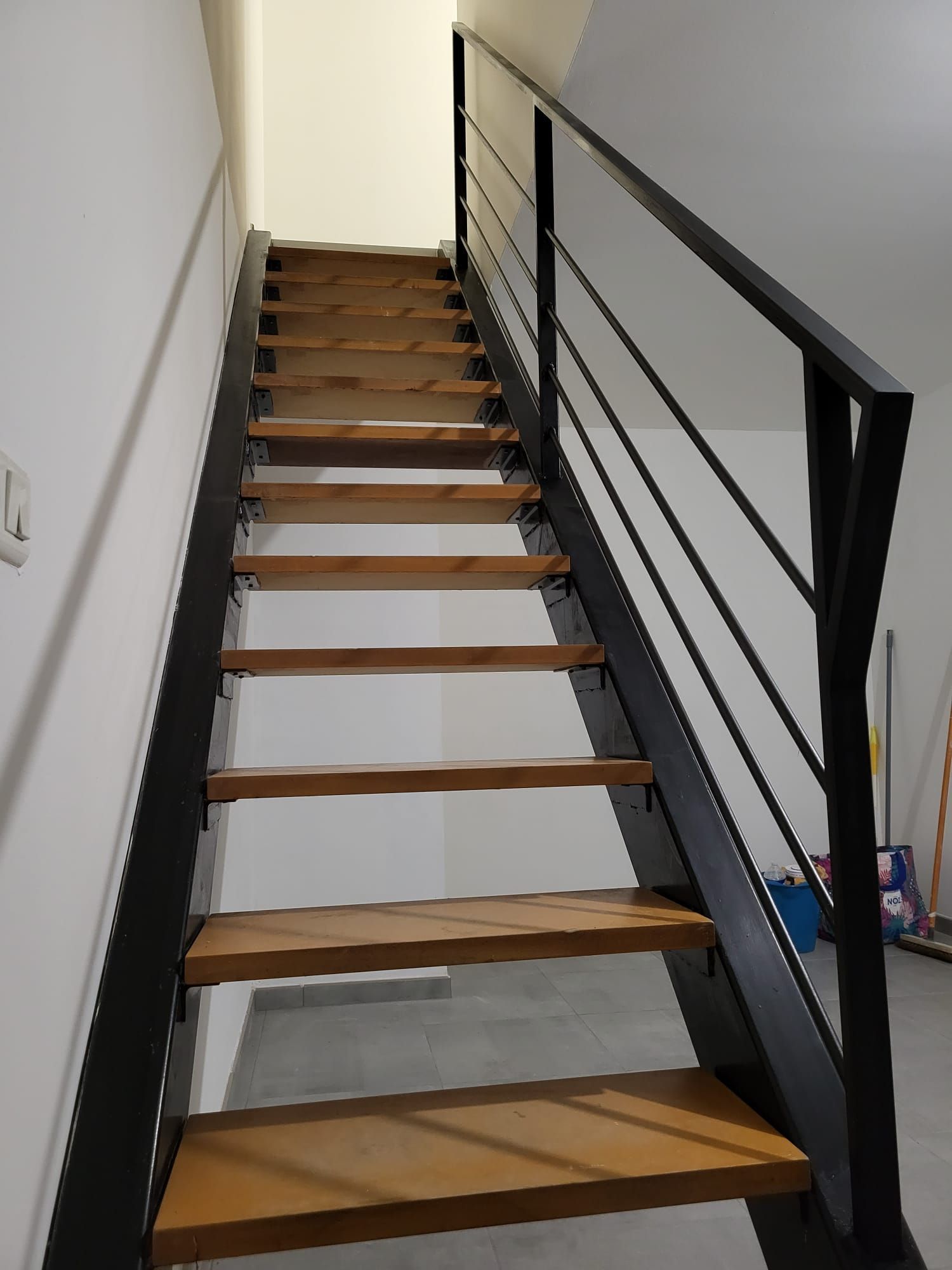 Une balustrade en métal borde une terrasse en pierre avec une plante en pot à gauche et un jacuzzi sur une plateforme surélevée derrière.
