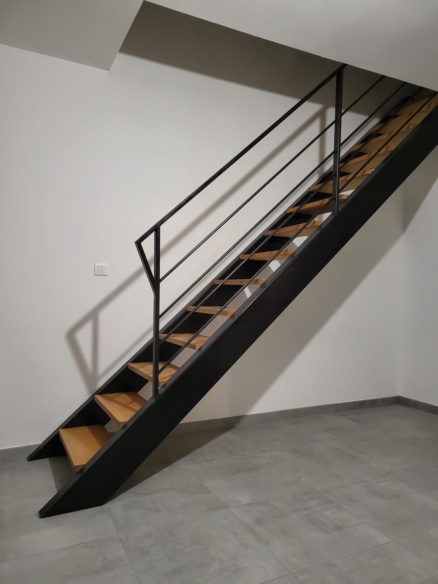 Une fenêtre dotée de barreaux de sécurité en métal disposés selon un motif géométrique unique et non parallèle.