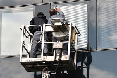 Zwei Männer putzen die Fenster eines Gebäudes.