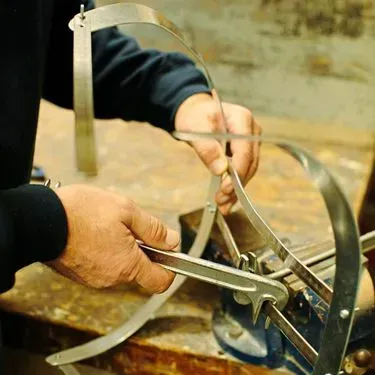 Eine Person montiert mit Werkzeugen einen Metallrahmen auf einer Werkbank.