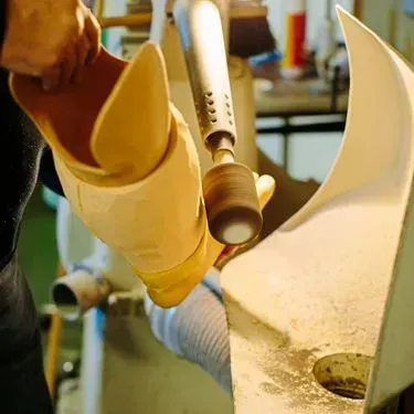 Eine Person bearbeitet mit einem Schleifwerkzeug eine Beinprothese in der Werkstatt