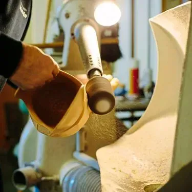 Eine Person schleift eine Beinprothese an einer Holzbearbeitungsmaschine