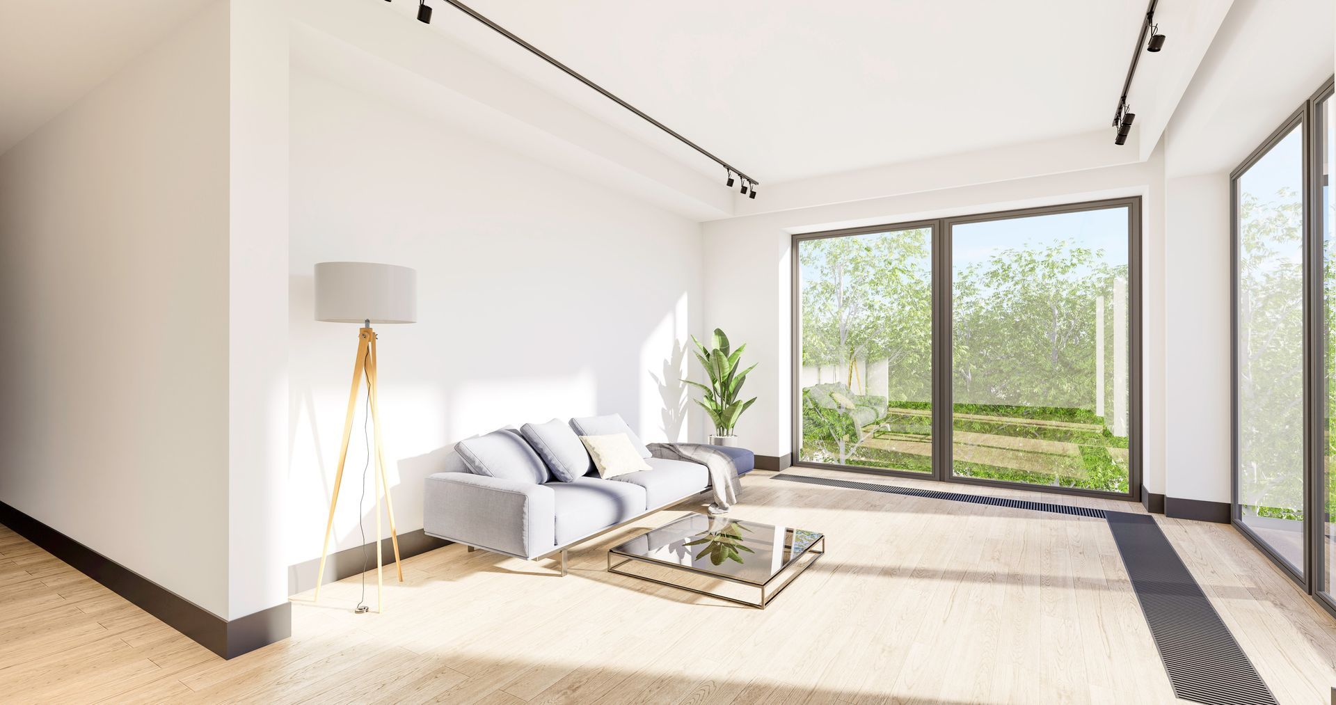 Salon moderne avec un canapé gris clair, une table basse en verre, un lampadaire et de grandes fenêtres donnant sur la verdure.