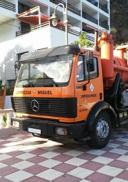 Un camión Mercedes naranja está estacionado frente a un edificio.