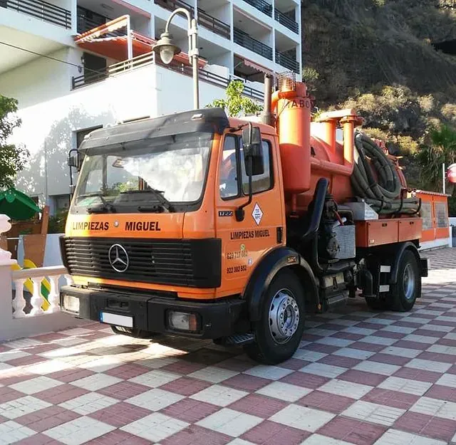 Una camioneta Mercedes naranja está estacionada frente a un edificio.