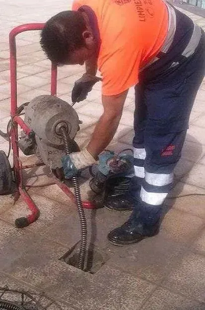 Un hombre está usando una máquina para sacar una serpiente de un agujero en el suelo.
