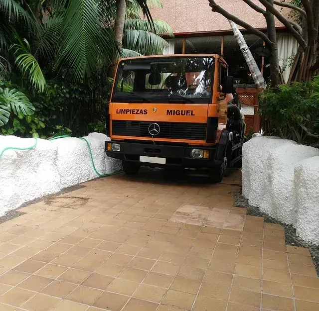 Una camioneta Mercedes naranja está estacionada en una entrada.