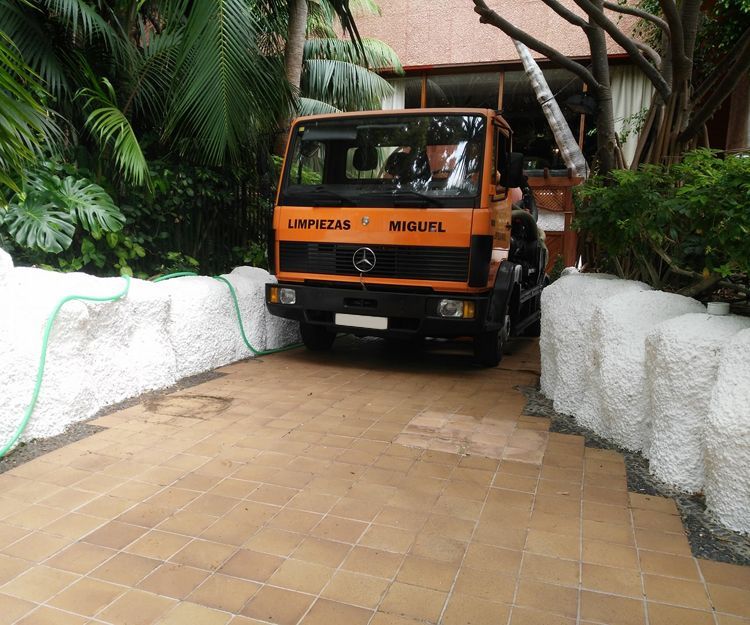 Una camioneta Mercedes naranja está estacionada en una entrada.