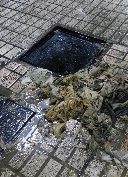 Un agujero en el suelo con mucha basura dentro.