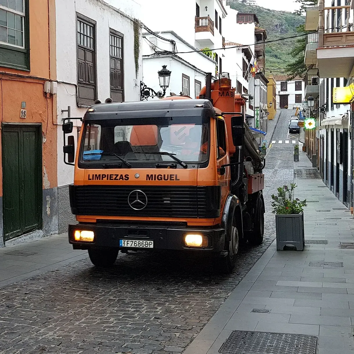 Un camión Mercedes circula por una calle adoquinada.
