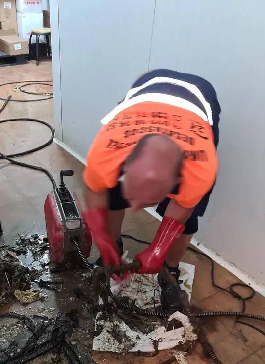 Un hombre está usando una máquina para sacar una serpiente de un agujero en el suelo.