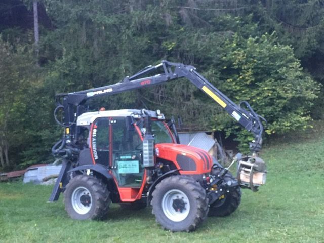 Un tracteur rouge et noir avec une grue attachée