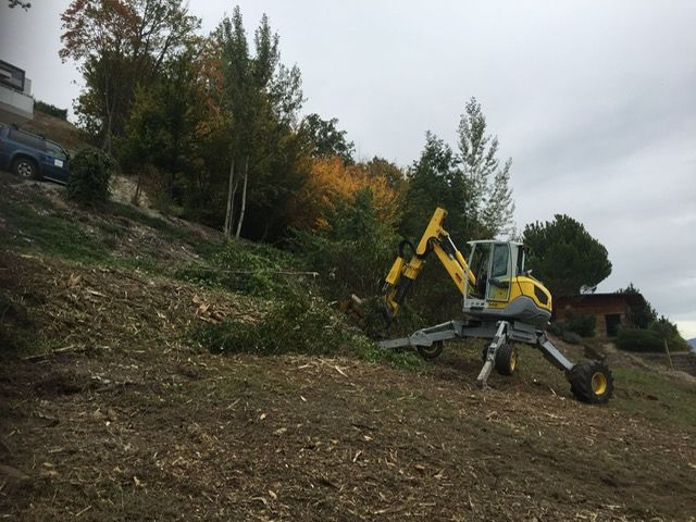 Une excavatrice jaune est assise au sommet d'une colline de terre.