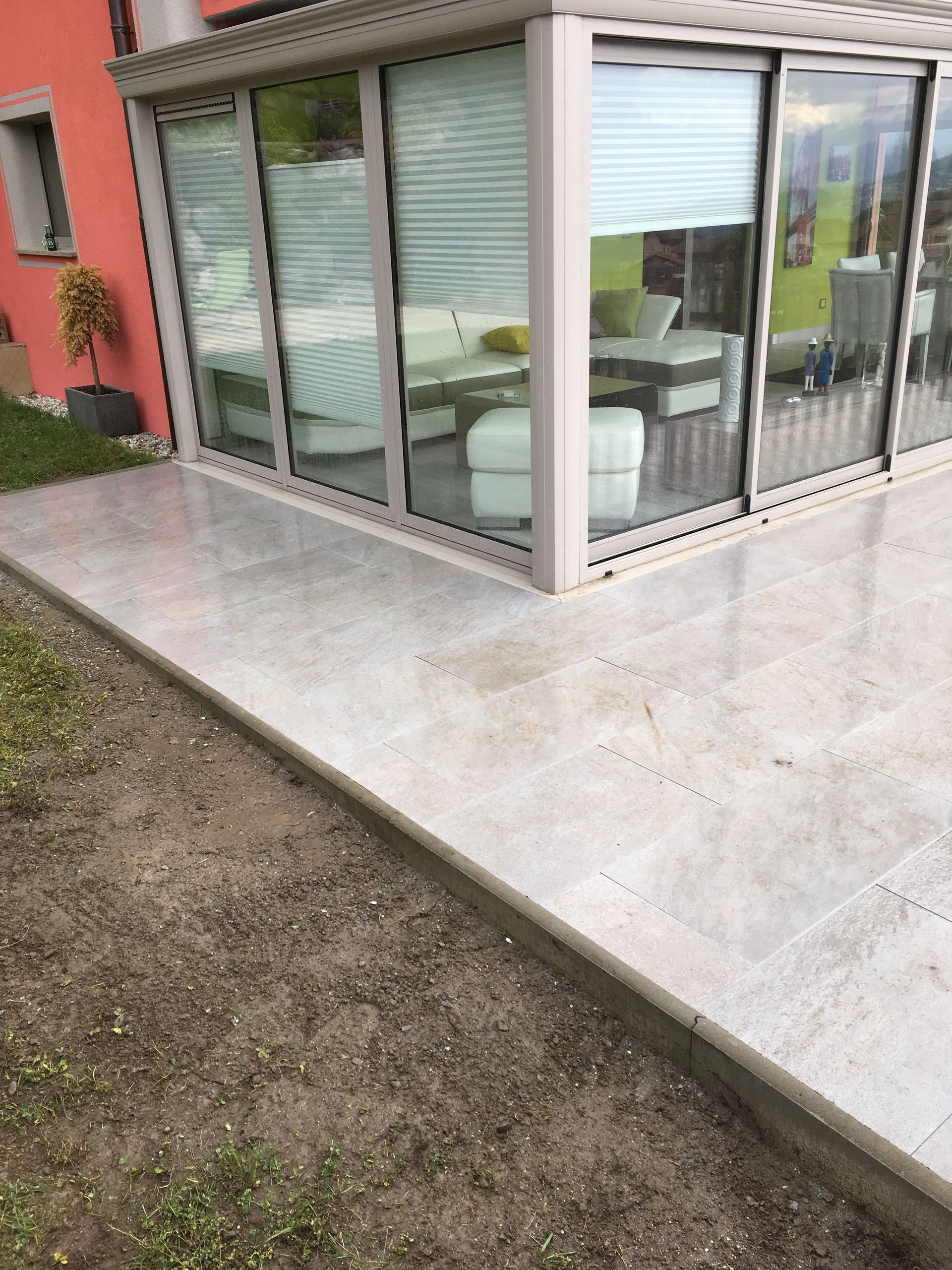 Il y a un patio devant une maison avec beaucoup de fenêtres.