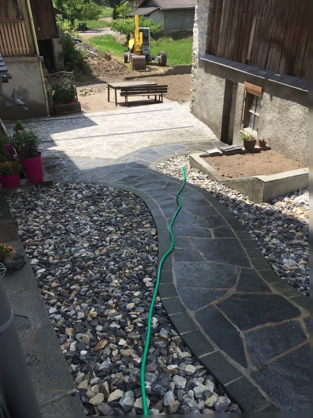 Un tuyau vert est relié à une passerelle en pierre.