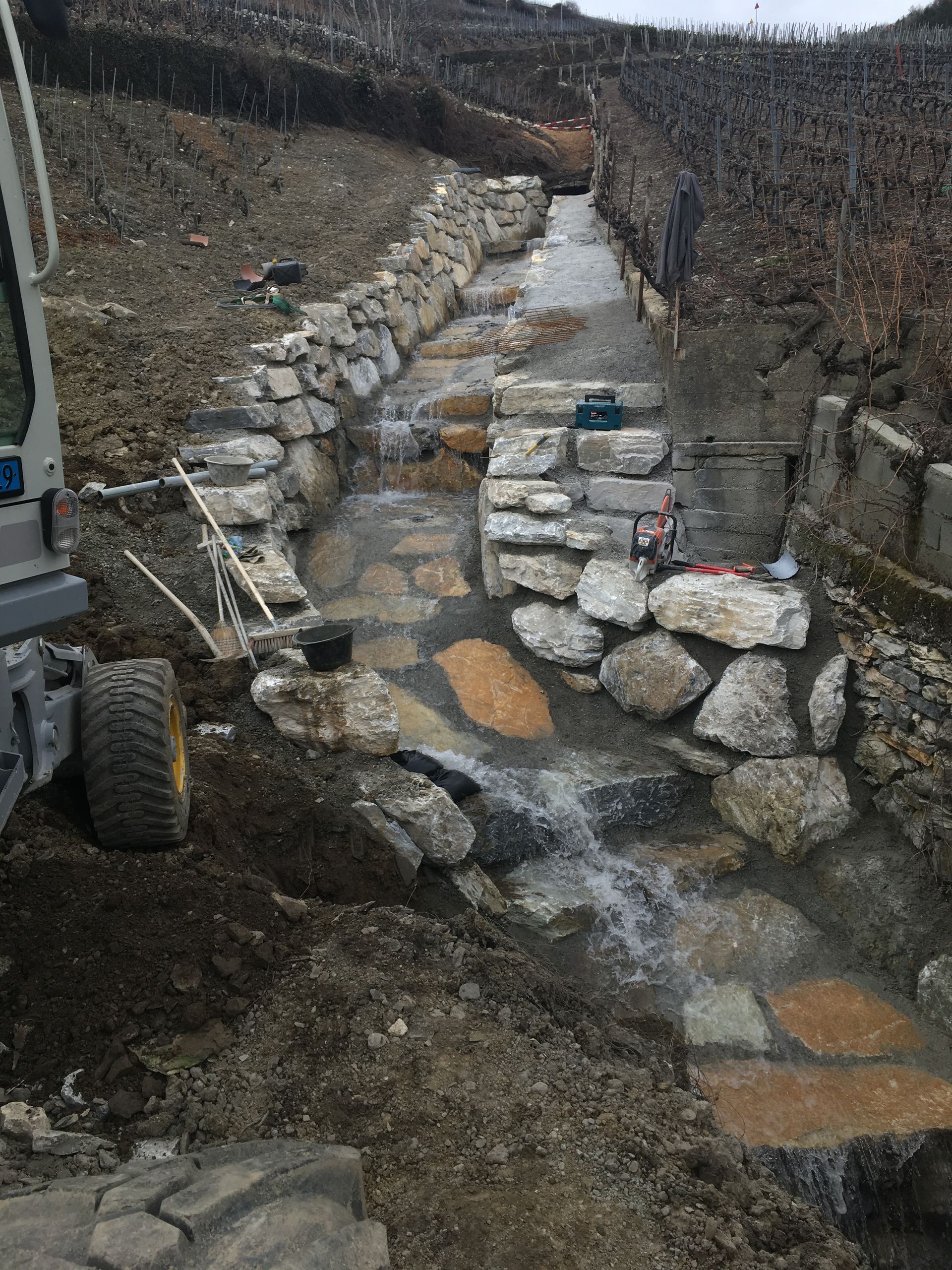 Un bulldozer roule sur un chemin de terre à côté d'un ruisseau.