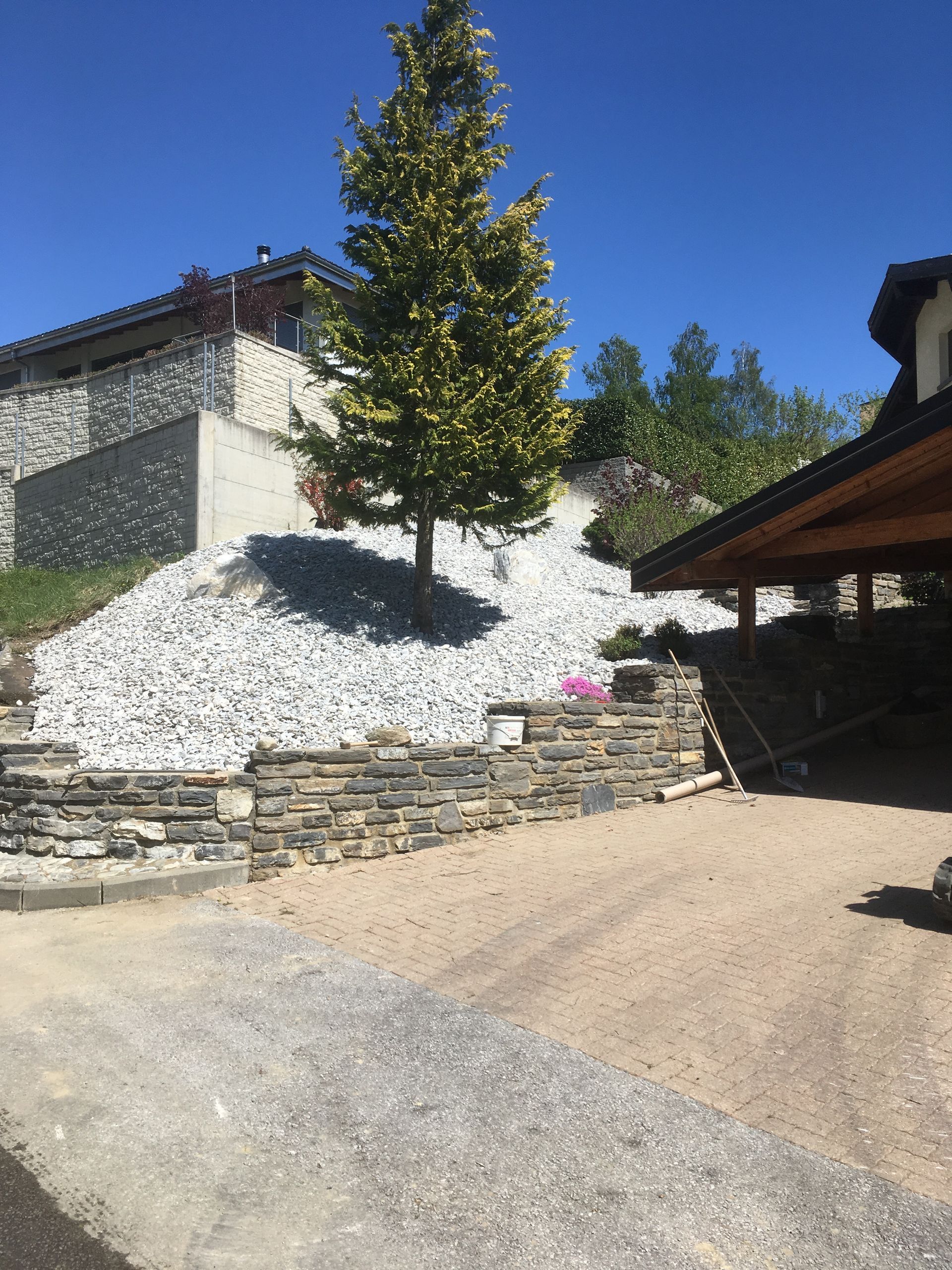 Une maison avec un mur de pierre et un arbre devant