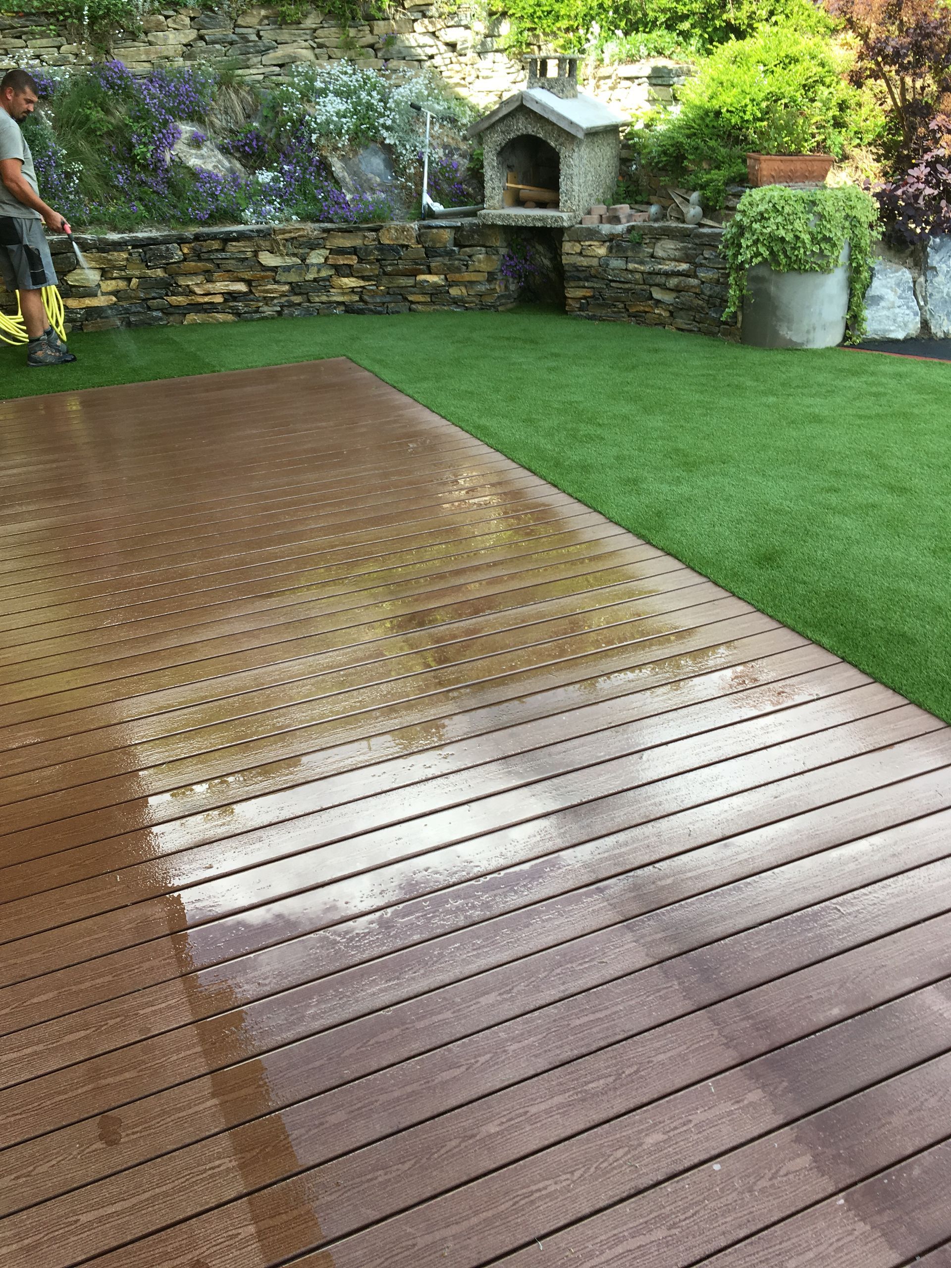 Un homme nettoie une terrasse en bois avec un nettoyeur haute pression.