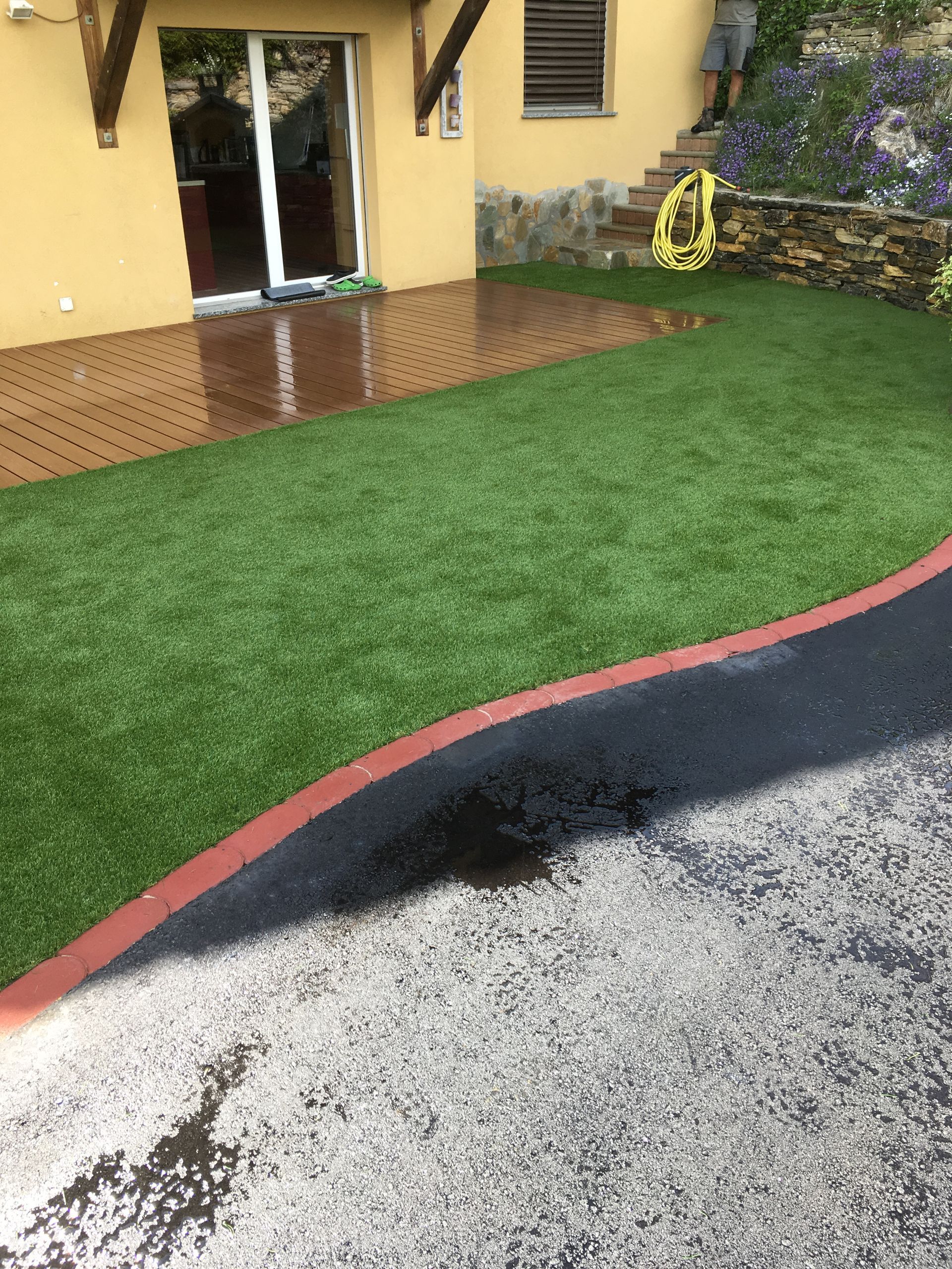 Une pelouse avec un tuyau jaune devant une maison