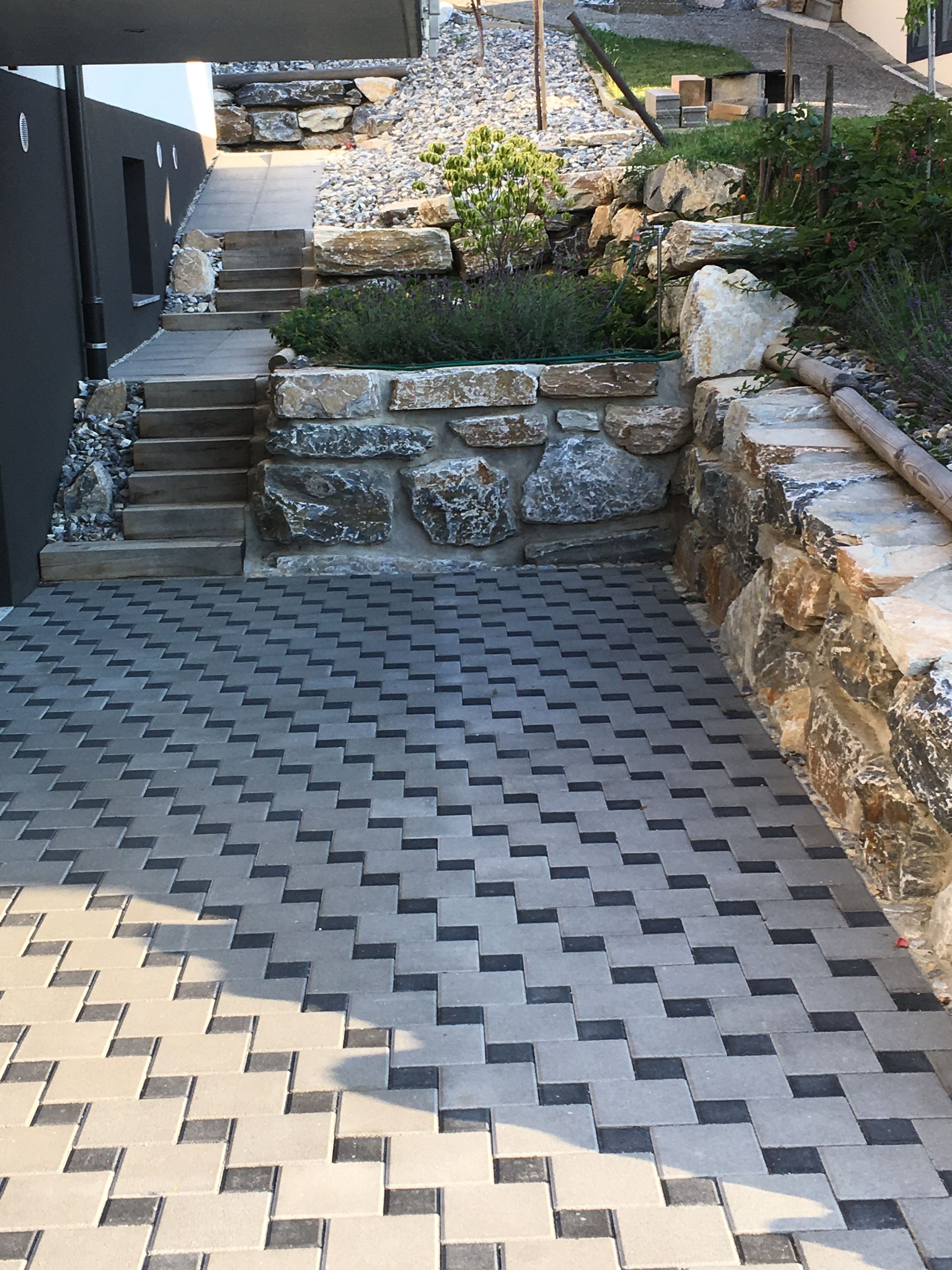 Une allée en briques avec des escaliers menant à un mur de pierre